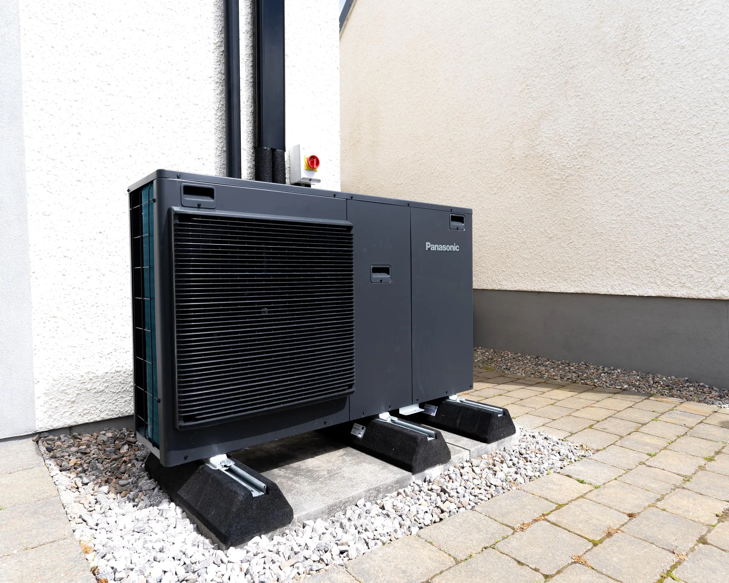 Anthracite Panasonic J-Series heat pump installed against a white harled wall in Tornagrain, near Inverness