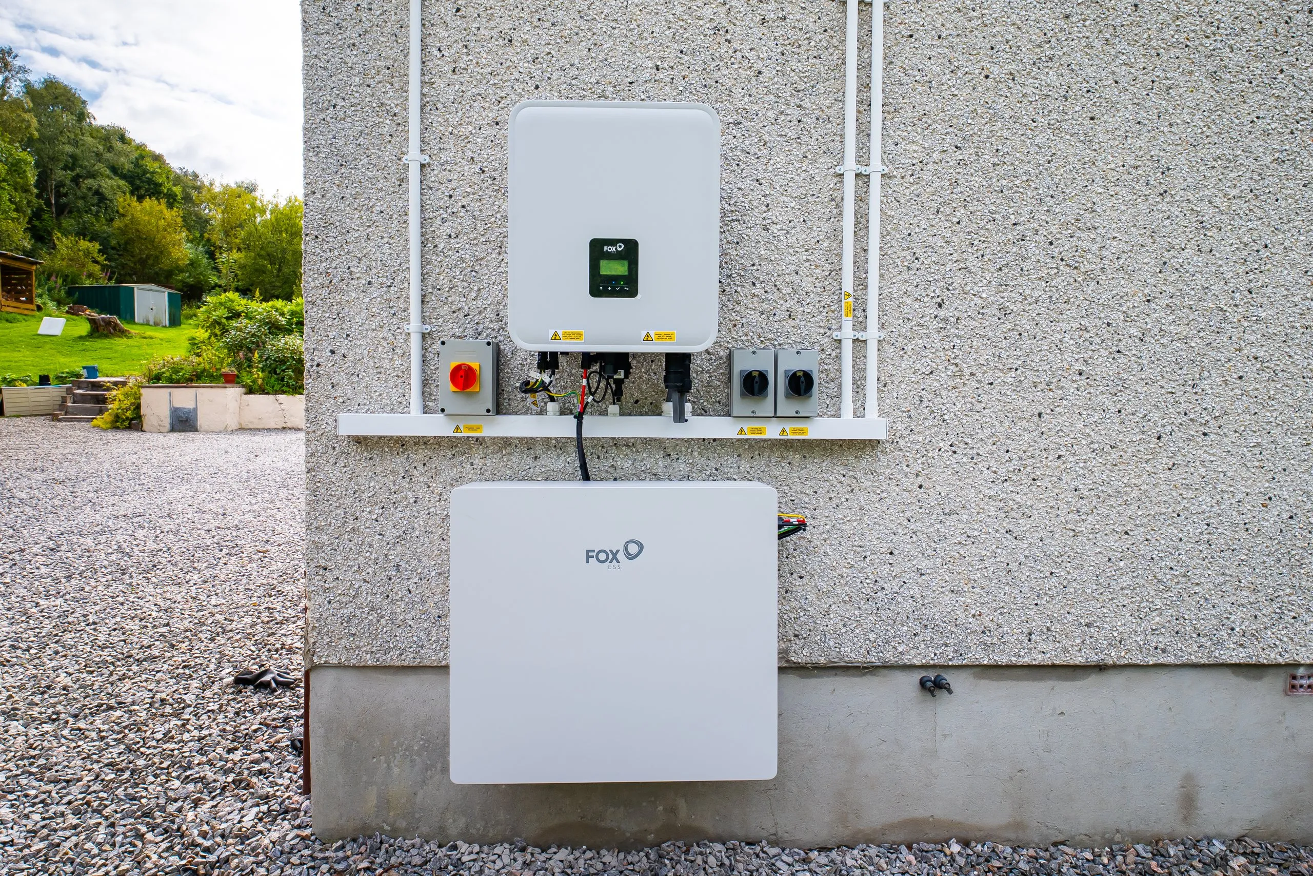 Fox hybrid inverter mounted above a Fox ESS battery on a harled house wall near Fortrose