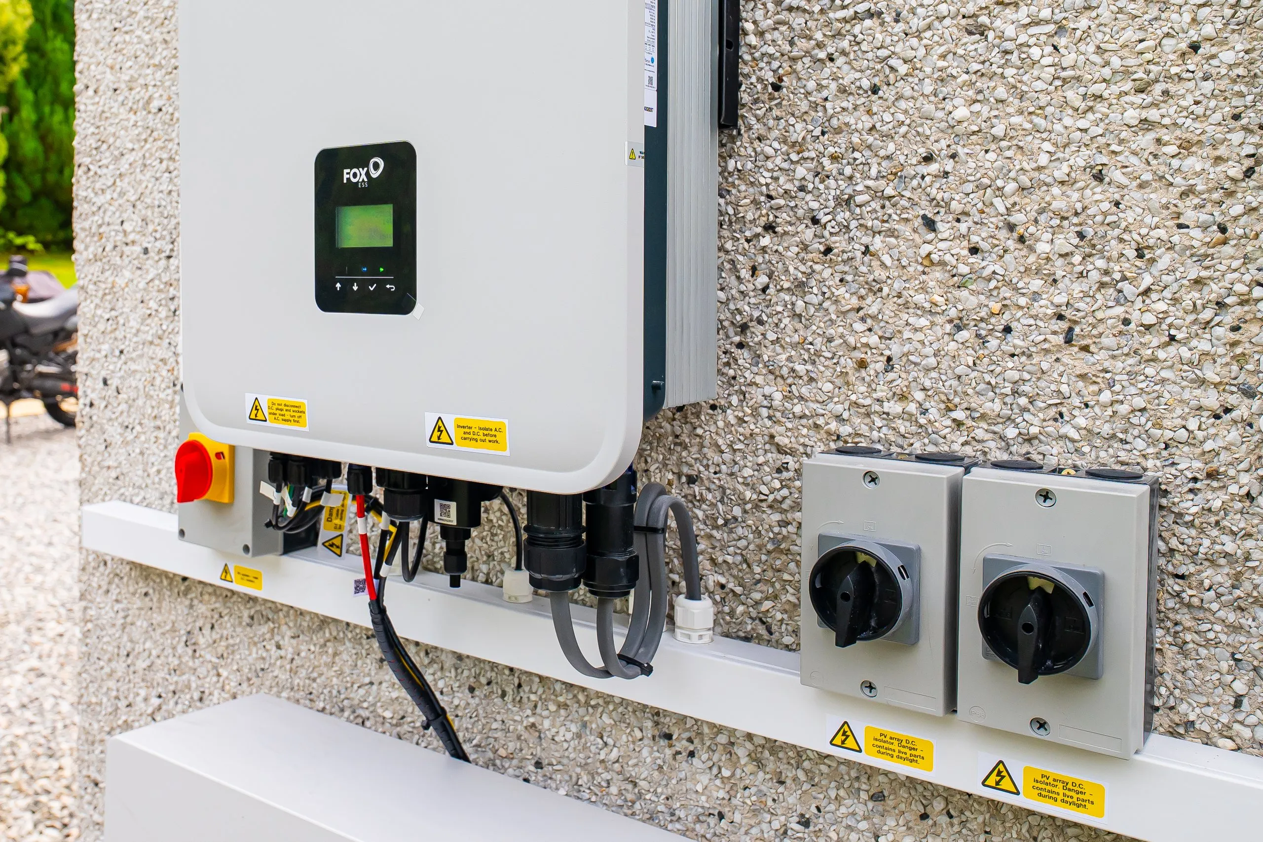 Close-up of the Fox ESS hybrid inverter display with PV array isolators alongside