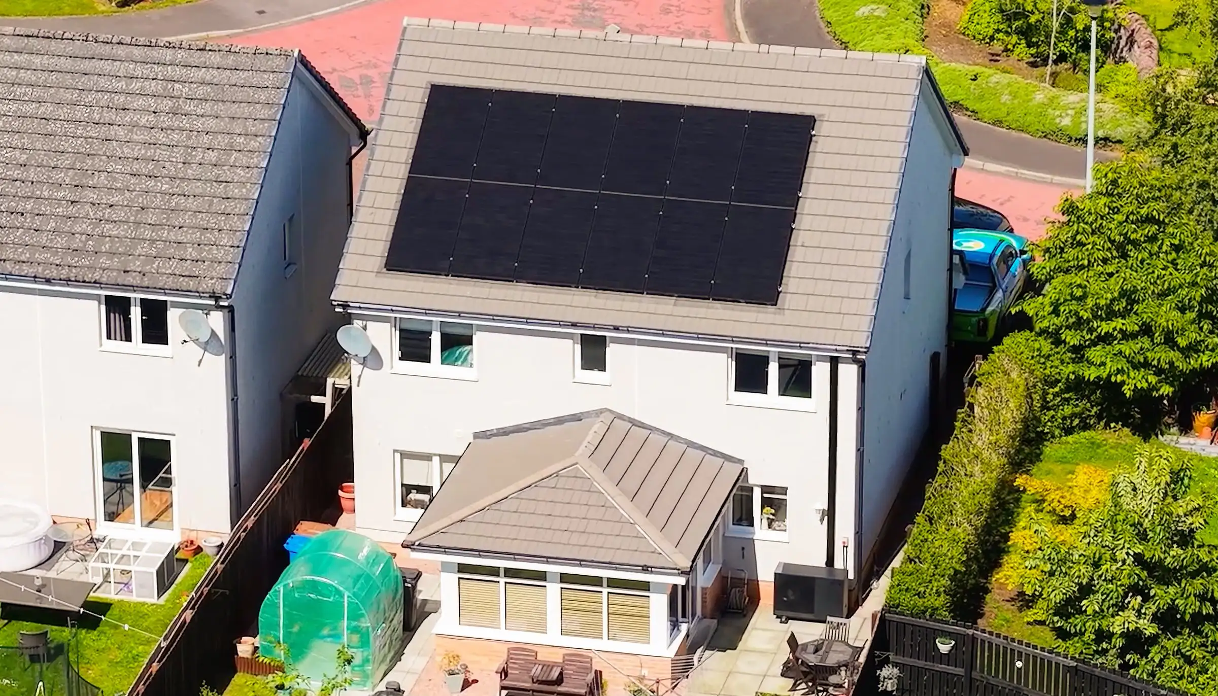 Drone view of a McInnes Group installation at a Scottish home — full rooftop solar array with an air source heat pump at the back door