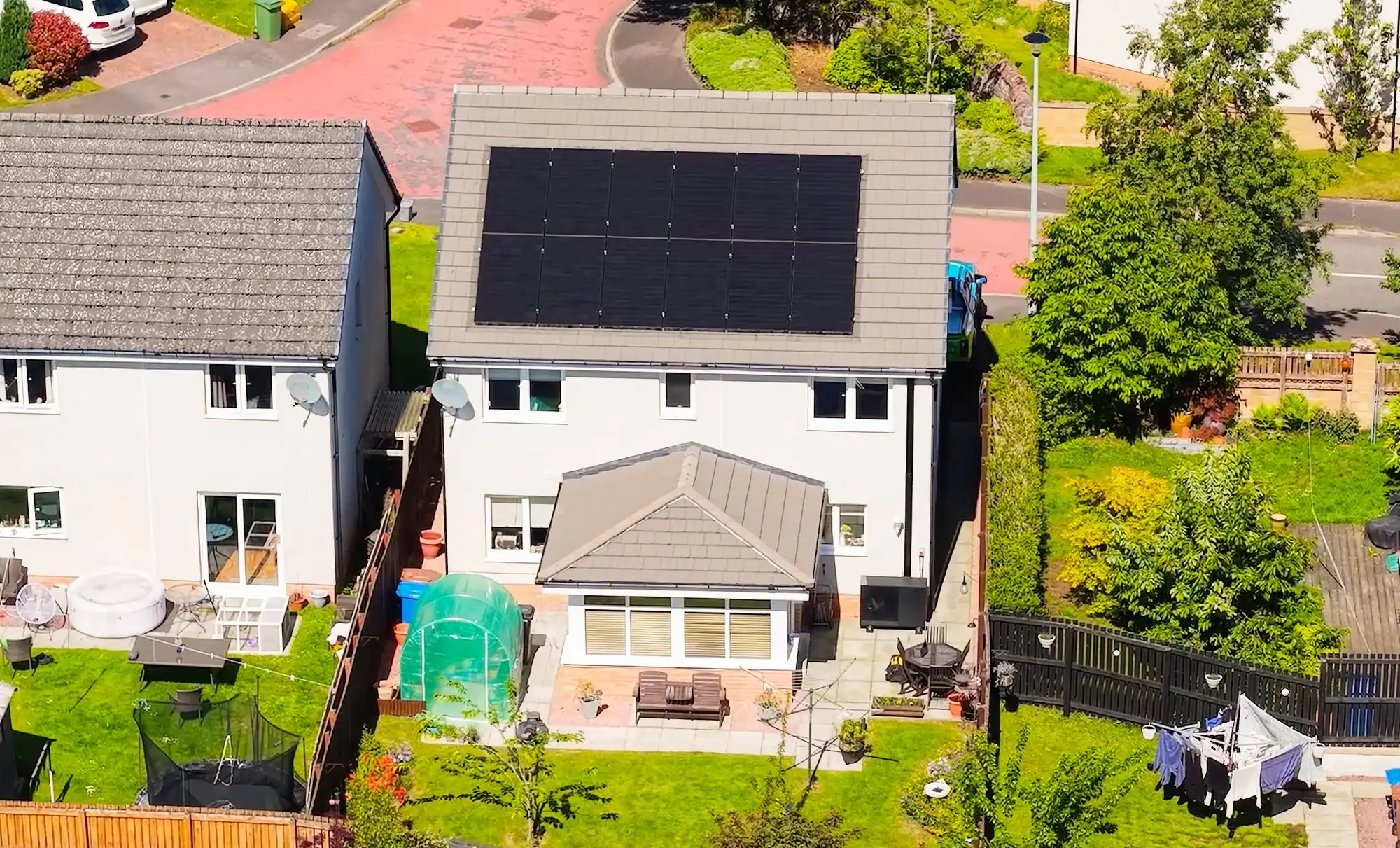 Drone view of a full rooftop solar array and air source heat pump installed by McInnes Group on a detached Scottish home